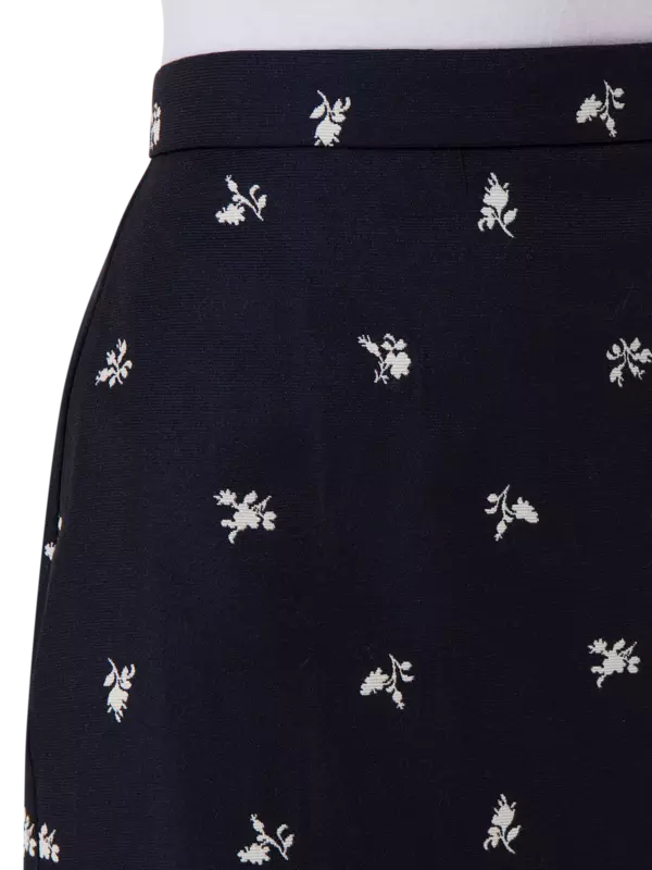 تنورة طويلة من قماش الجاكار بقصة ضيقة من الأعلى وواسعة من الأسفل مزينة بزهور صغيرة