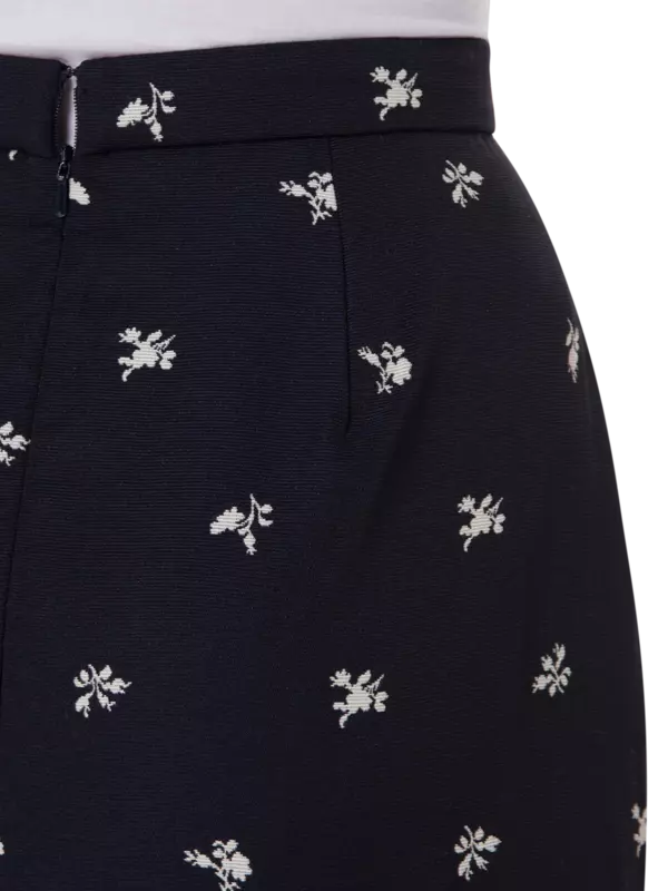 تنورة طويلة من قماش الجاكار بقصة ضيقة من الأعلى وواسعة من الأسفل مزينة بزهور صغيرة